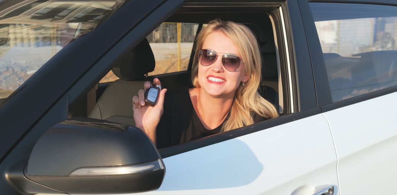Smiling woman holding keys to new car in the driver's seat