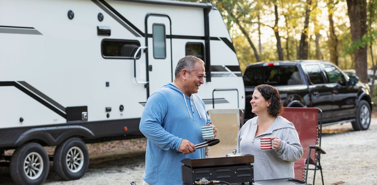 Middle-aged couple cooking on a camp stove in front of their RV