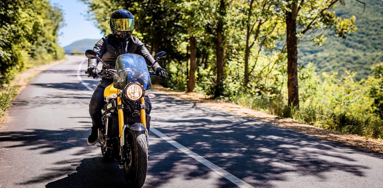 Motorcyclist in safety gear riding on a country road