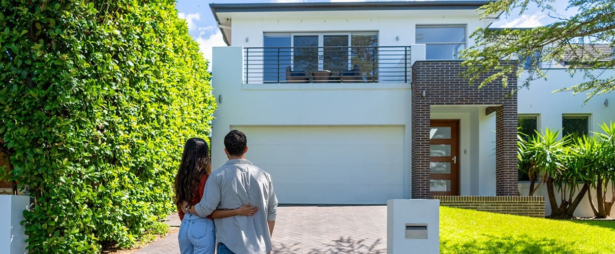 Young couple embracing and facing their new house
