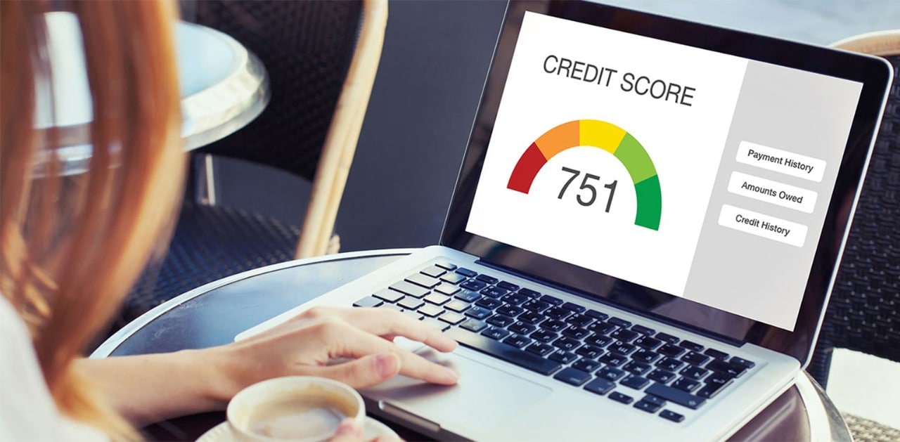 A woman typing at a laptop that has a credit score of 751 displayed