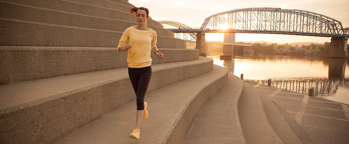 Woman jogging along Serpentine Wall with the Ohio River in the background