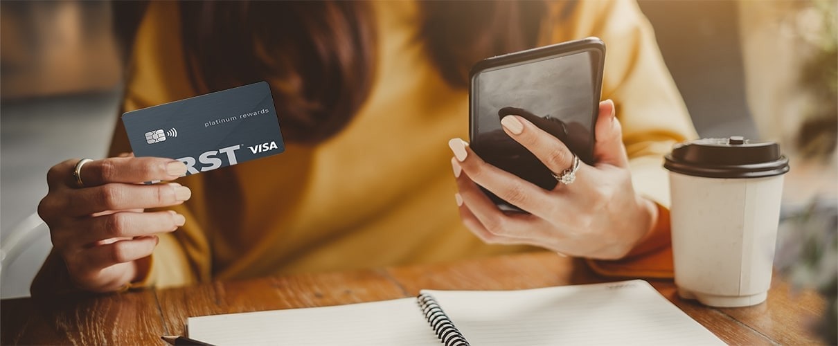 Woman holding smartphone and First Financial Platinum Rewards card