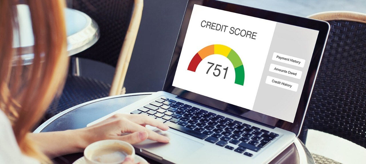 A woman typing at a laptop that has a credit score of 751 displayed