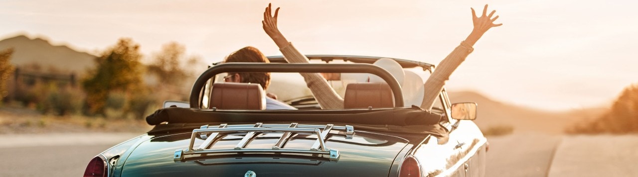 Young couple driving classic convertible on highway