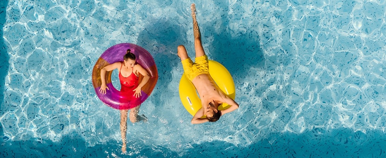 Overhead view of young Caucasian couple relaxing in rafts in swimming pool