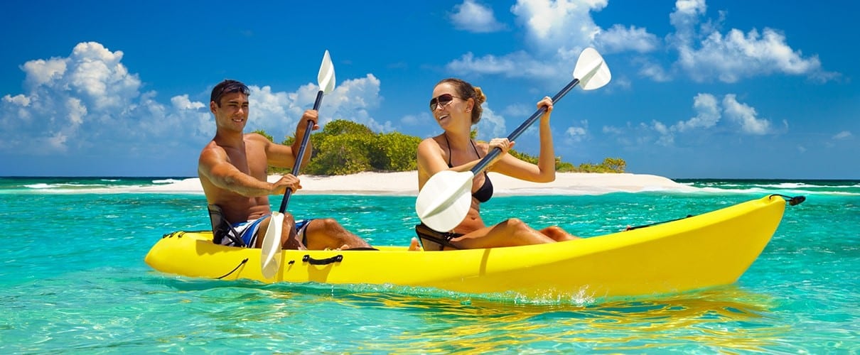 Young couple kayaking with a beach in the background