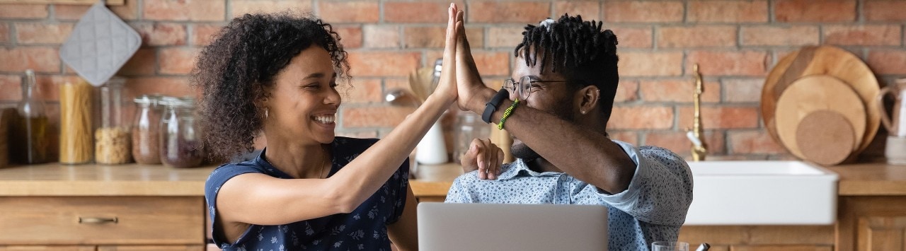 African American couple high fiving at desk. 