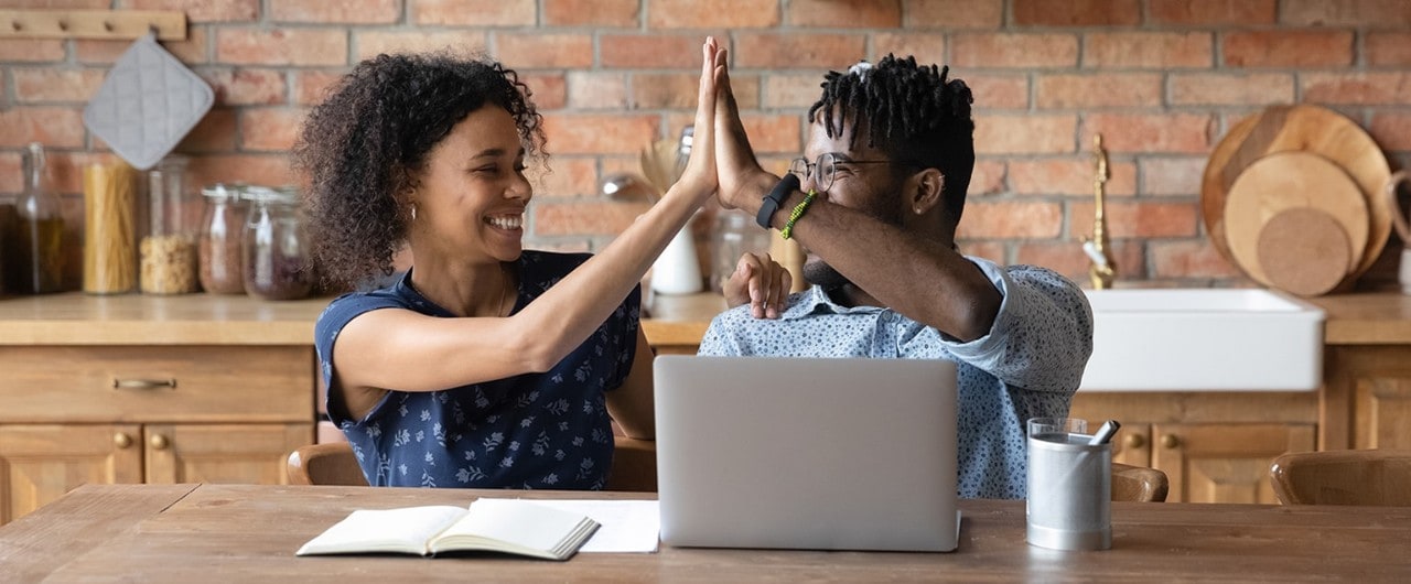 African American couple high fiving at desk. 