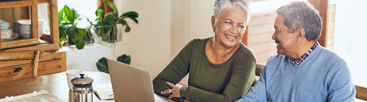 Smiling senior couple reviewing finances at a laptop