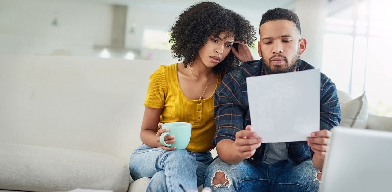 Concerned African-American couple reviewing financial document