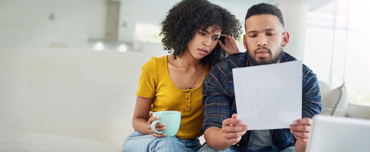 Concerned African-American couple reviewing financial document