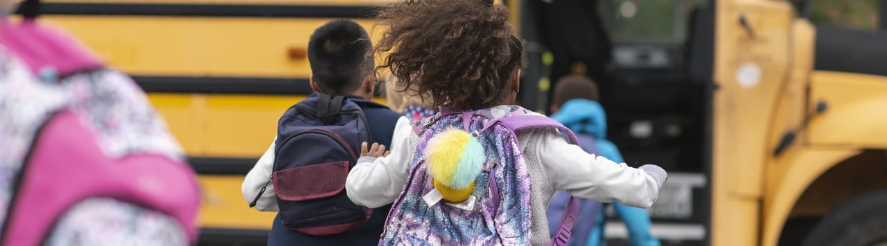 Group of children with backpacks running to school bus