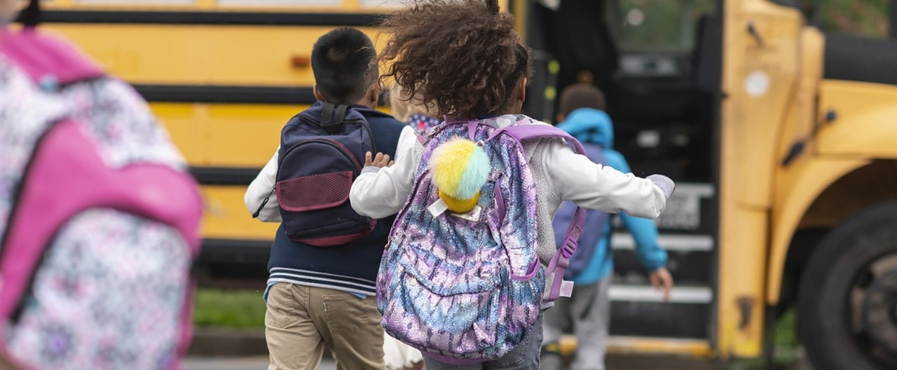 Group of children with backpacks running to school bus