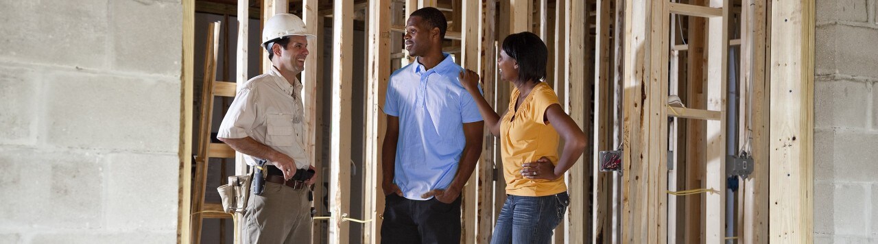 African-American couple talking to contractor in partially built home