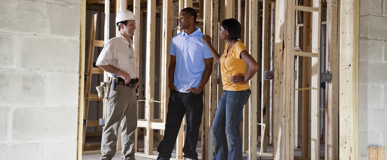 African-American couple talking to contractor in partially built home