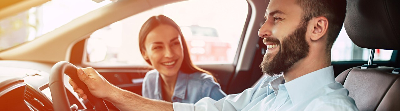 Happy, young couple driving car