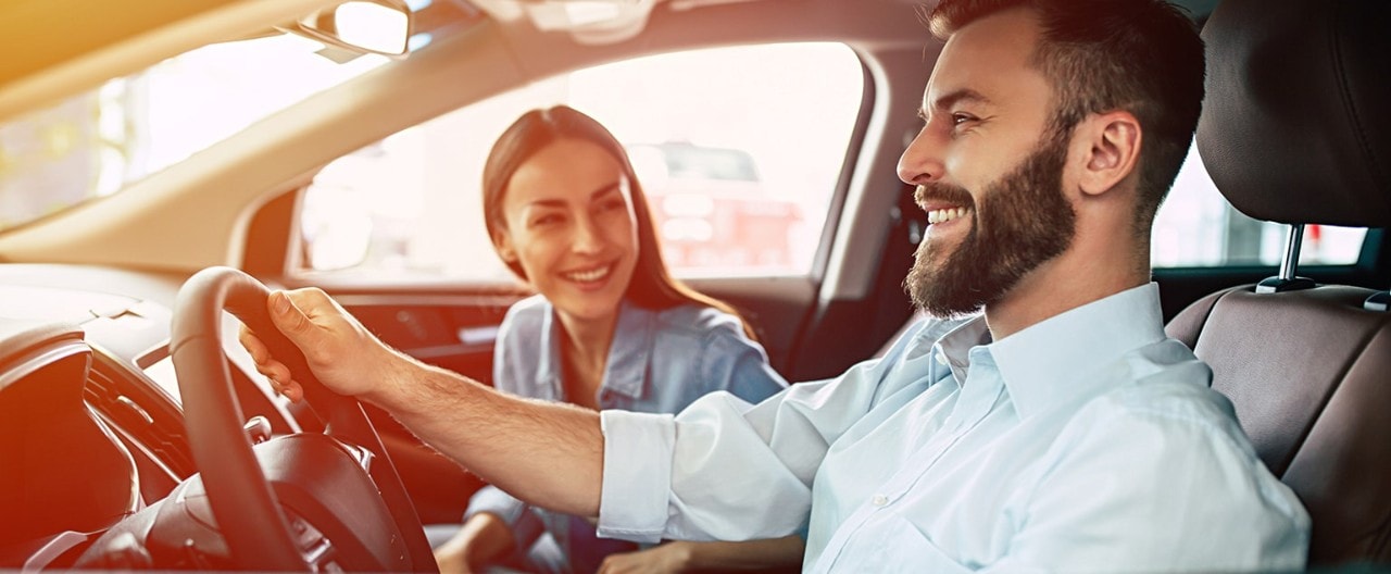 Happy, young couple driving car