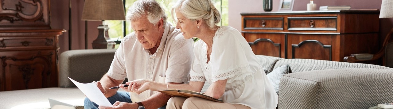Senior couple reviewing financial documents with laptop