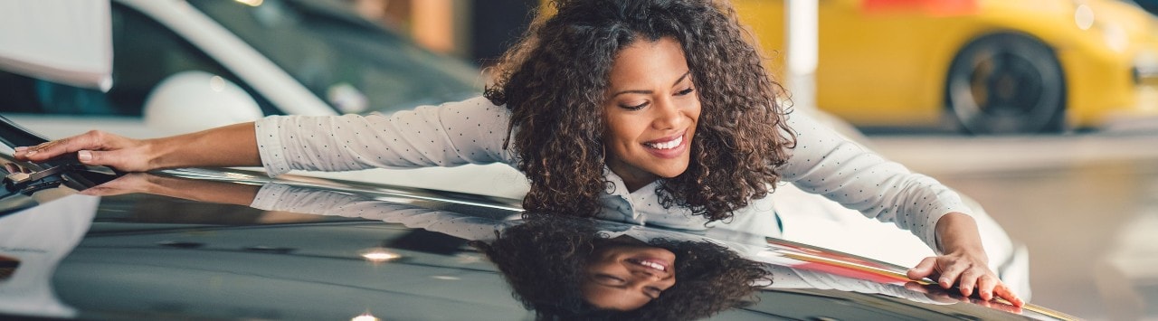 Woman admiring a luxury car in a dealership