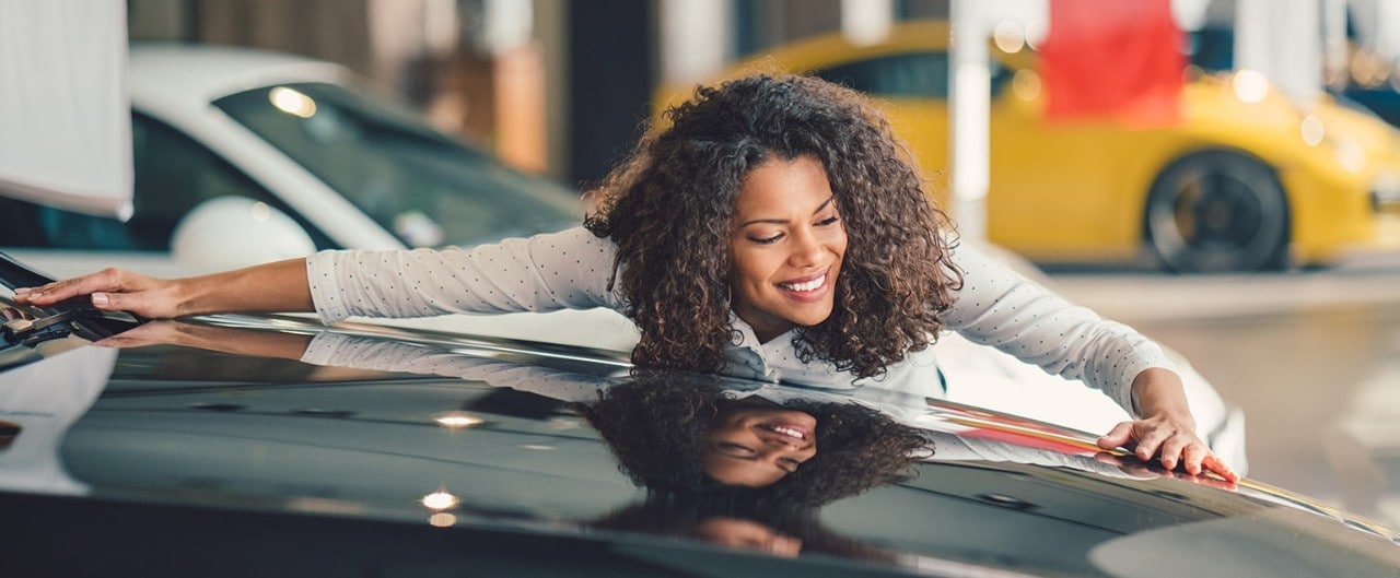 Woman admiring a luxury car in a dealership