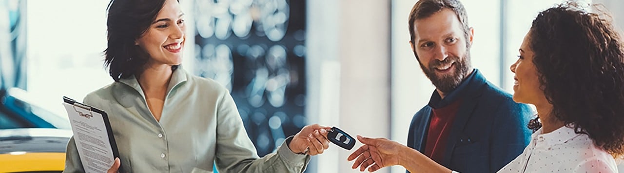 Car saleswoman handing keys to multiracial couple