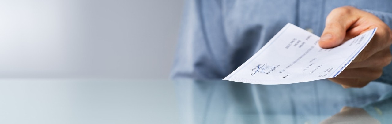 Man holding a check as he hands it to another person