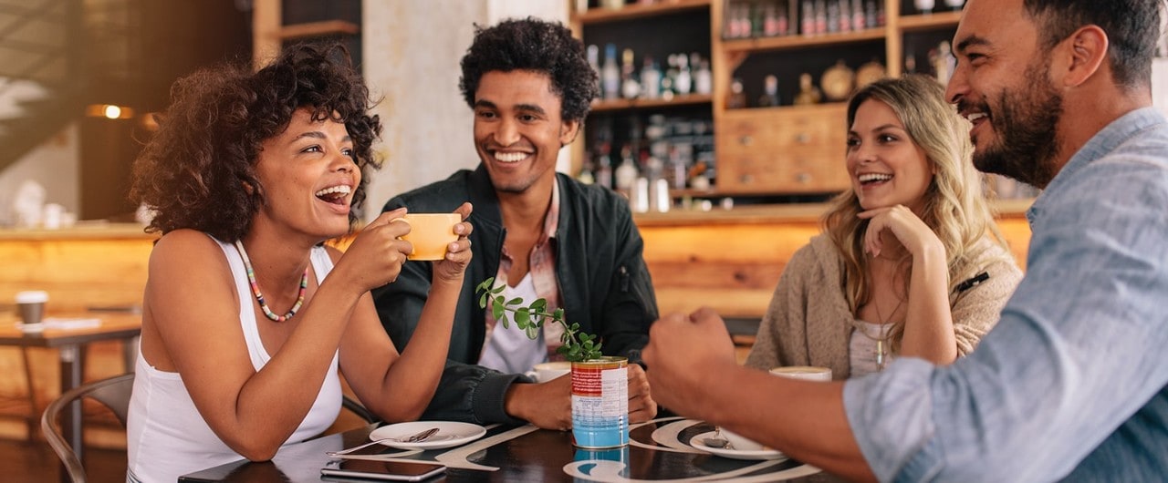 Diverse group of friends sitting at table in coffee bar