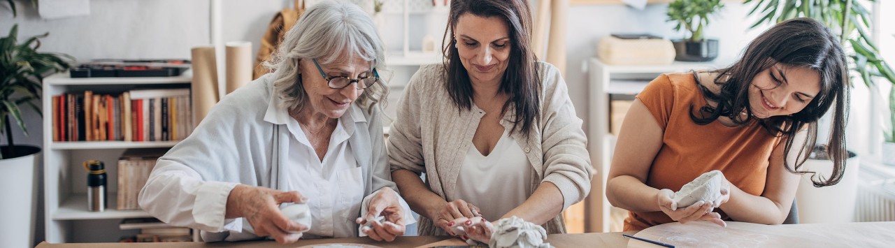 Woman working on pottery project with her mother and teenaged daughter