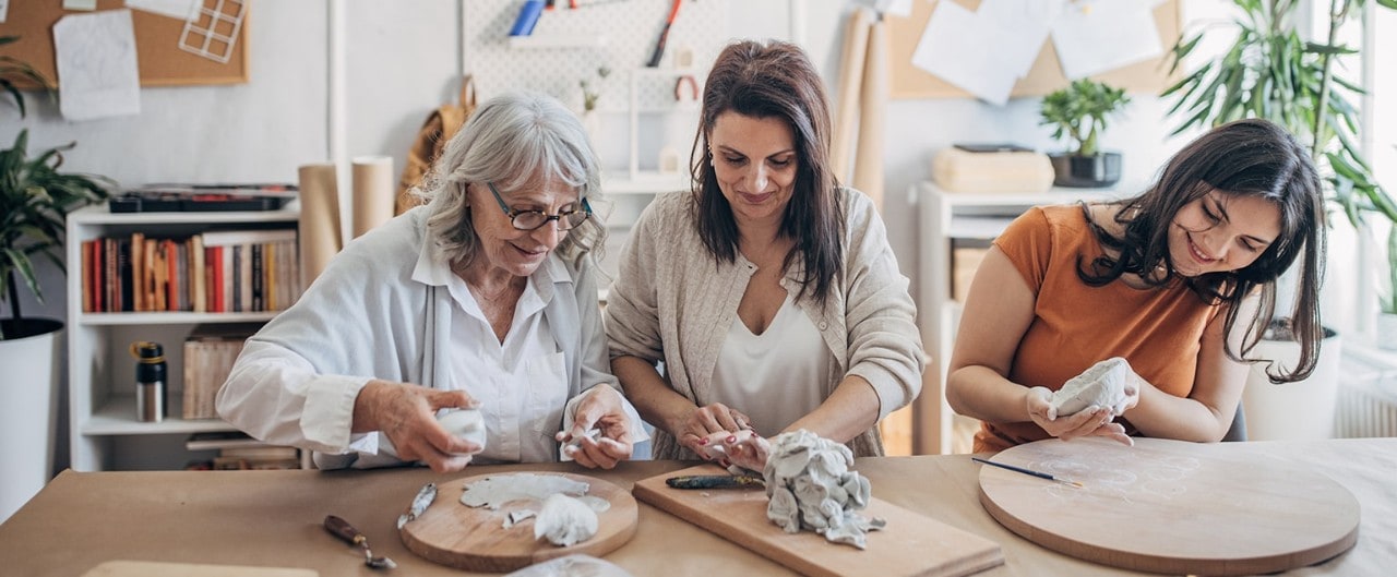 Woman working on pottery project with her mother and teenaged daughter