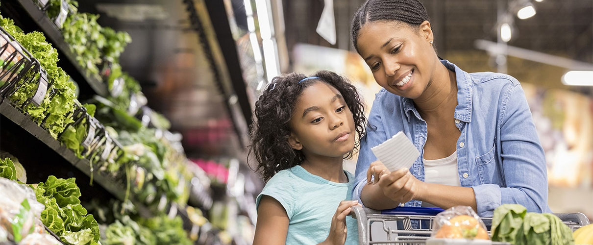 African-American mother and daughter grocery shopping in produce aisle