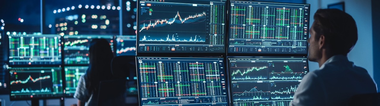 Financial analysts reviewing stock data on multiple monitors