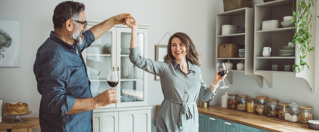 A retired couple dance together in the kitchen after finalizing their estate planning documents