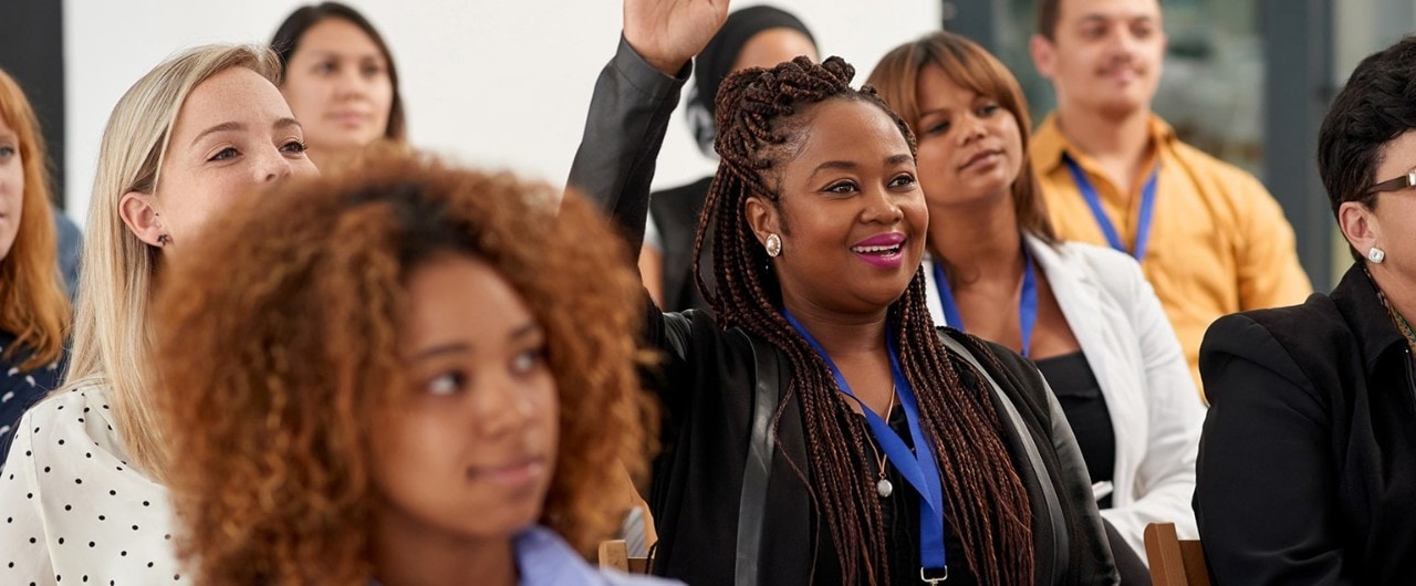 African-American woman raising her hand during a conference