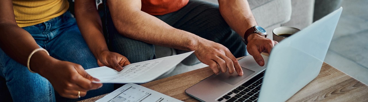 African-American couple using laptop and reviewing financial documents