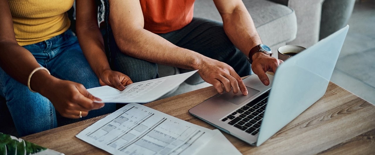 African-American couple using laptop and reviewing financial documents