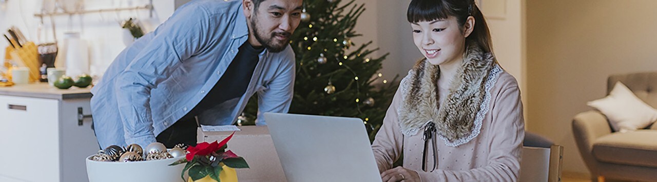 Asian couple at kitchen table looking at desktop during holidays