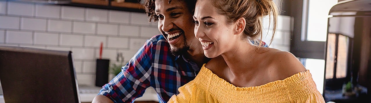 Multiracial couple at table looking at laptop