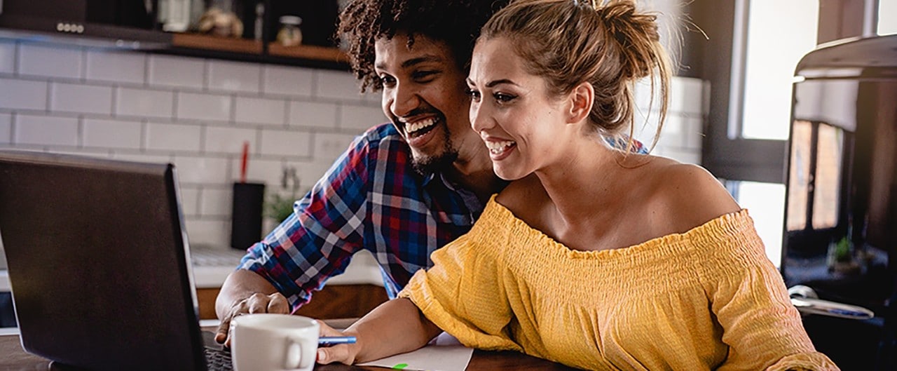 Multiracial couple at table looking at laptop