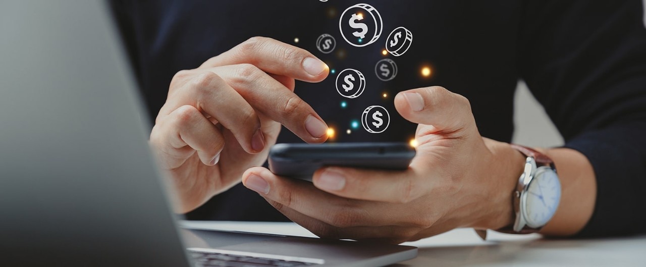 Man holding cell phone with graphic coins coming to life out of the screen.