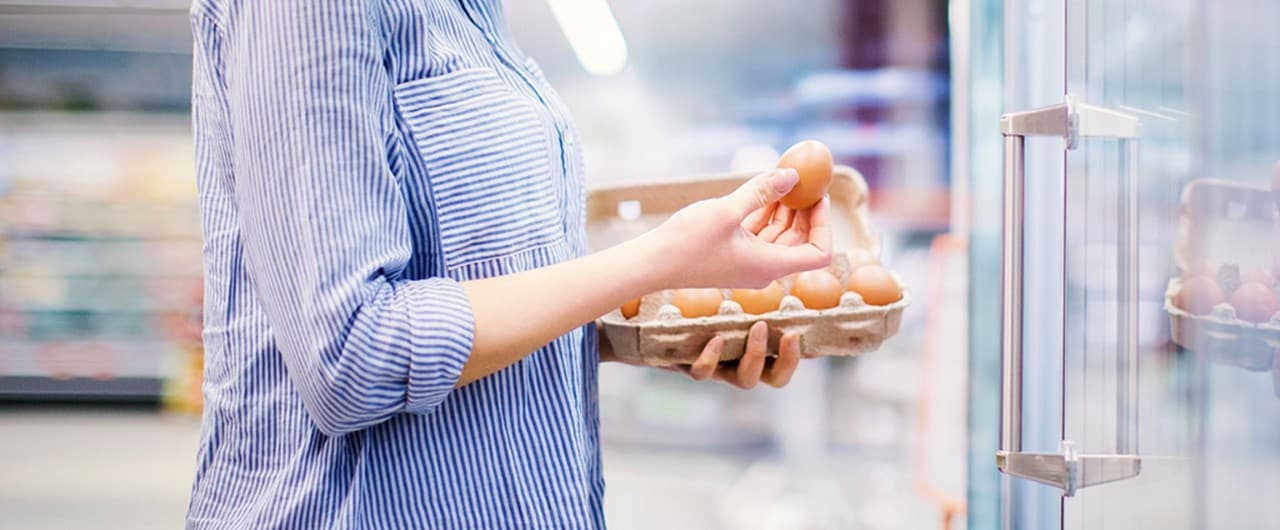 Woman purchasing eggs at a grocery store