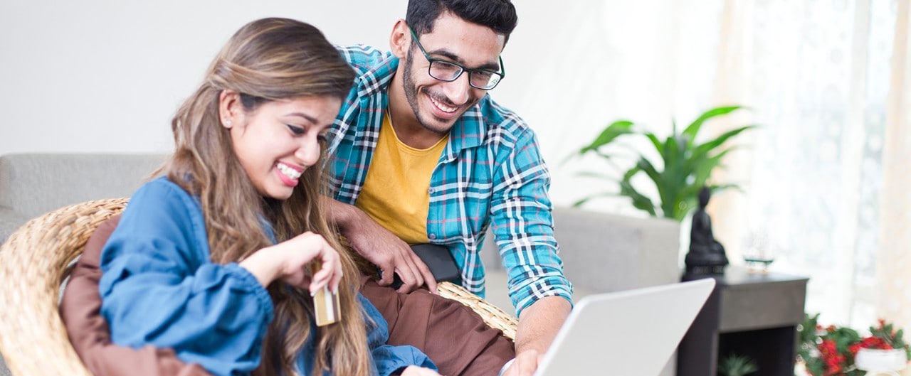 Two people looking at a laptop holding a credit card.