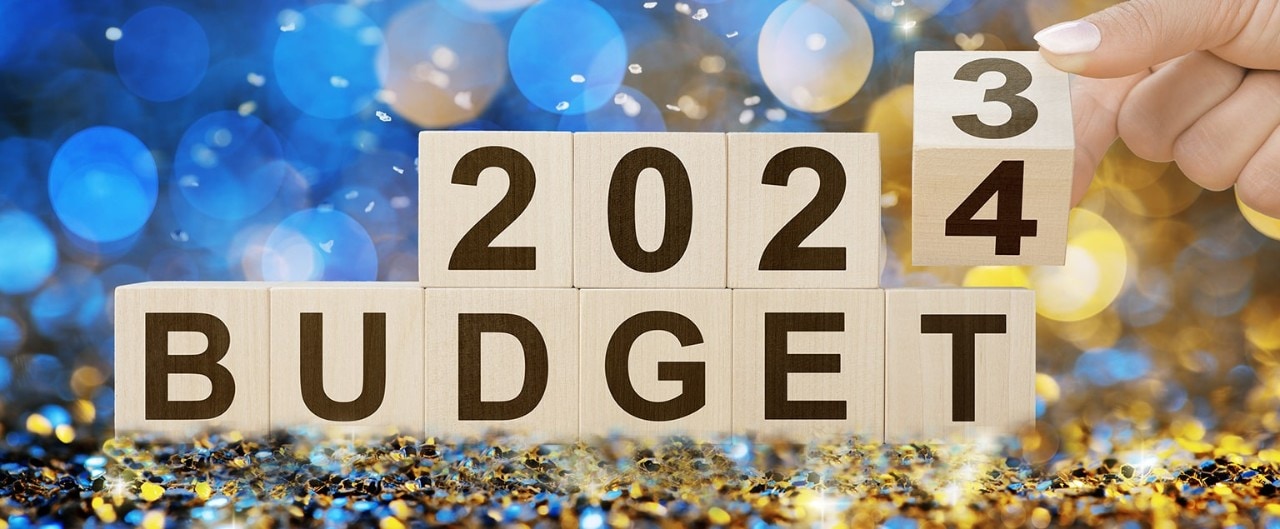 Woman flipping wooden cube from 2023 budget to 2024 budget on confetti background