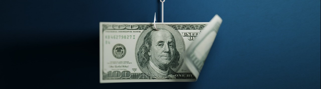 One hundred American dollar banknote on blue background. American dollar banknote is hooked by a fishing hook. Horizontal composition with selective focus and copy space. Great use for American dollar currency and financial concepts.