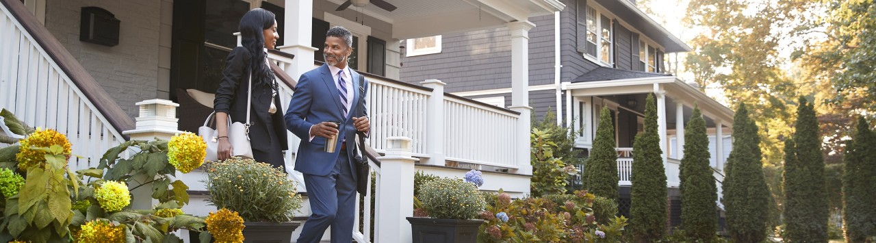 African-American couple walking down front steps of home in residential neighborhood