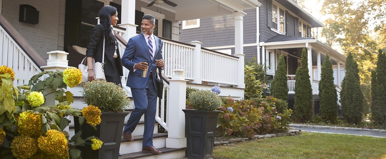 African-American couple walking down front steps of home in residential neighborhood