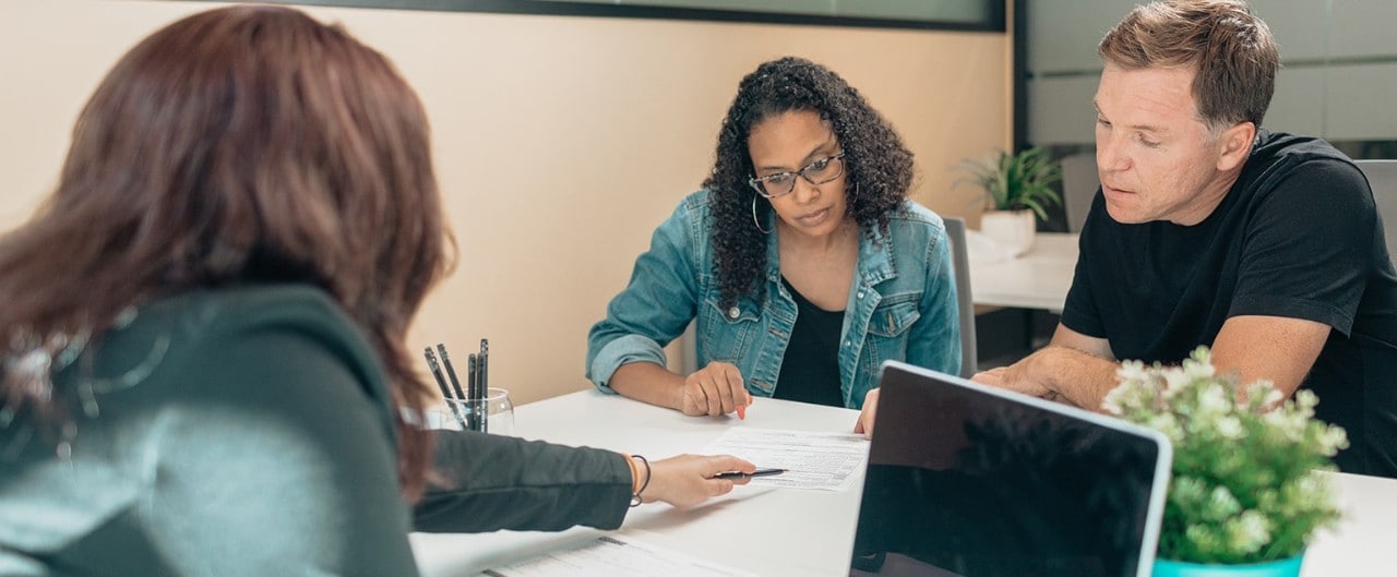 A couple reviews the portfolio construction of their investments with a financial planner as part of their wealth goal-setting process