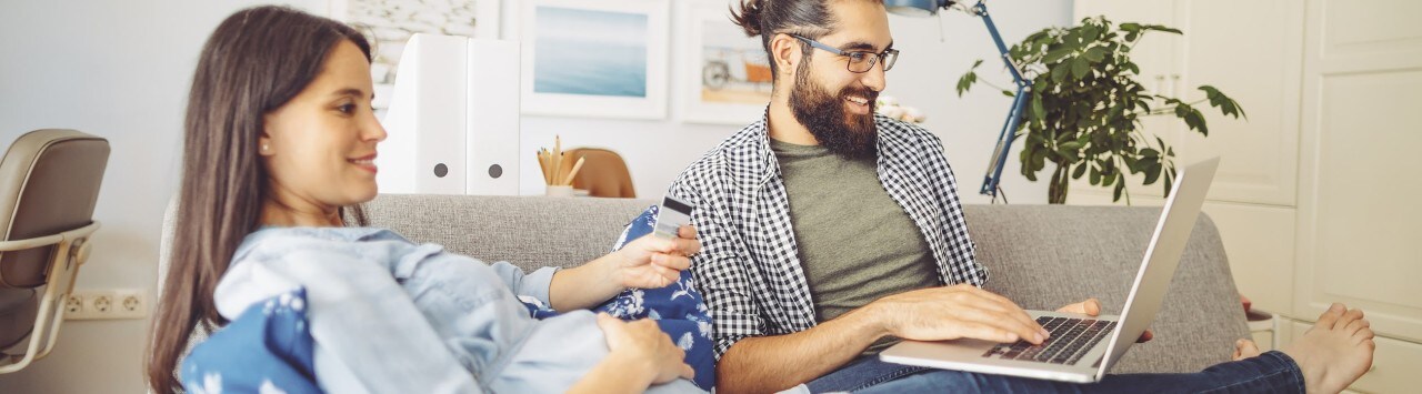 Man using laptop on couch with pregnant wife