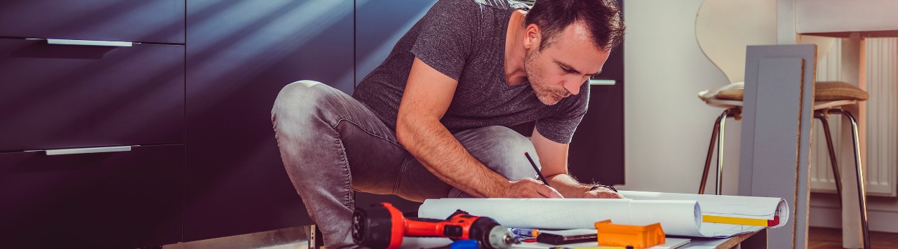 Man working on a new kitchen installation and looking at blueprints