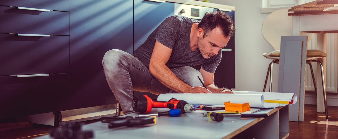 Man working on a new kitchen installation and looking at blueprints